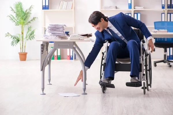 Молодой работник в инвалидной коляске работает в офисе — стоковое фото