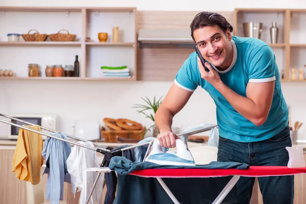 Joven marido haciendo planchado de ropa en casa — Foto de Stock