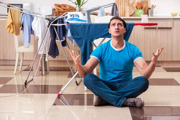 Genç adam evde çamaşır ütülüyor. 