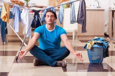 Genç adam evde çamaşır ütülüyor. 