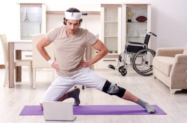 Evde egzersiz yapan yaralı genç adam. 