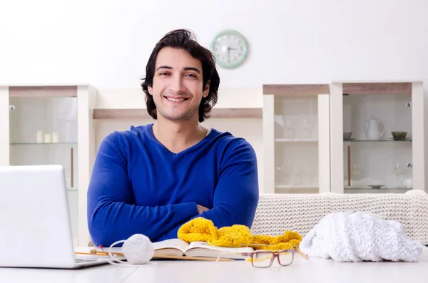 Young good looking man knitting at home