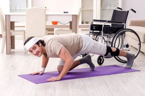 Injured young man doing exercises at home — Stock Photo, Image