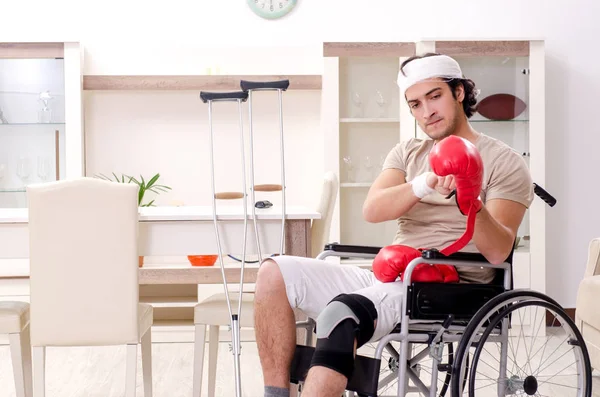 Injured young man doing exercises at home — Stock Photo, Image