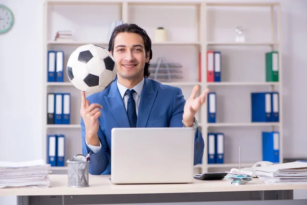 Jovem empresário bonito com bola de futebol no escritório — Fotografia de Stock