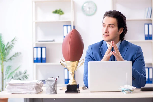 Молодой привлекательный бизнесмен с мячом для регби в офисе — стоковое фото