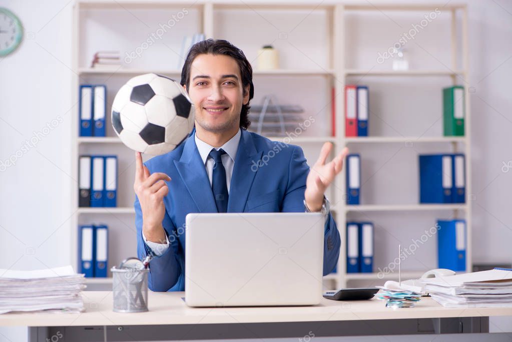 Young handsome businessman with soccer ball in the office 