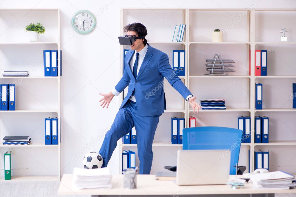 Young handsome businessman playing soccer with virtual glasses 