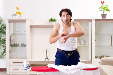 Genç adam yatak odasında ütü yapıyor.