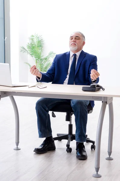 Hombre de negocios envejecido haciendo ejercicios de yoga en la oficina —  Fotos de Stock