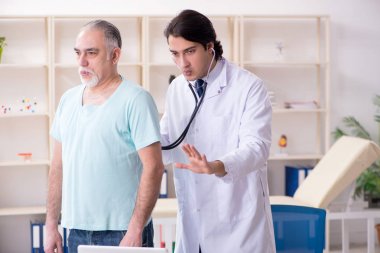 Yaşlı adam genç erkek doktoru ziyaret ediyor. 