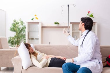Genç, yakışıklı doktor, kadın hastayı evinde ziyaret ediyor. 