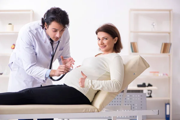 Vieja embarazada visitando joven médico masculino — Foto de Stock