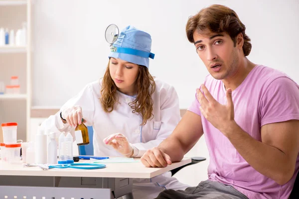 Joven hombre guapo visitando joven médico otorrinolaringólogo —  Fotos de Stock