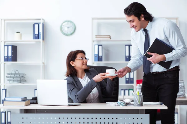 Old female boss and young male employee in the office