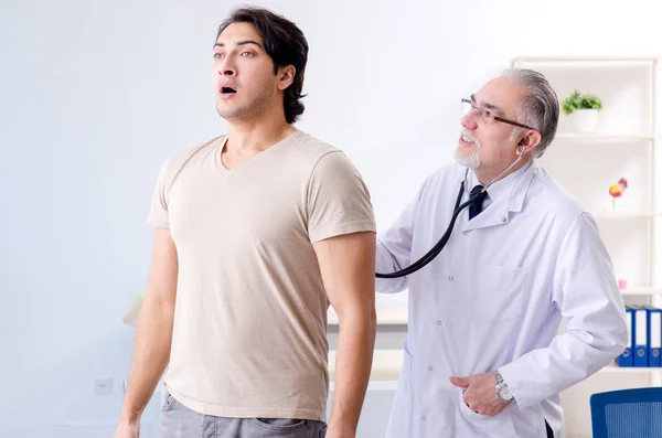 Jonge mannelijke patiënt bezoeken oude dokter — Stockfoto
