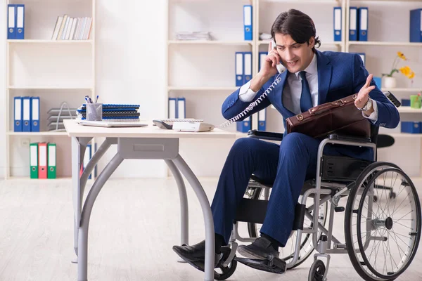Молодий чоловік працівник в інвалідному візку працює в офісі — стокове фото