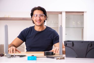 Evdeki mobilyaları tamir eden genç adam. 