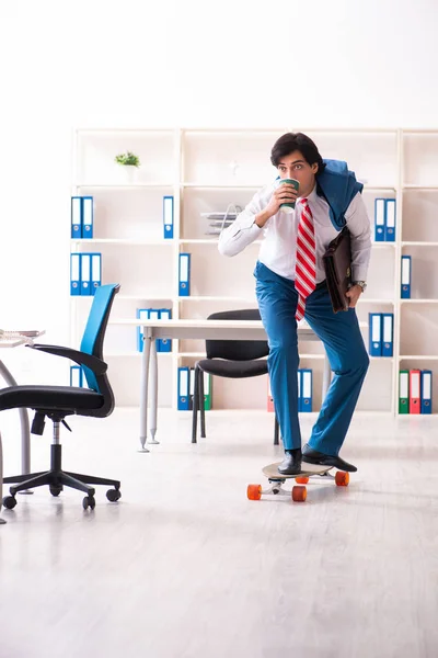 Ung stilig affärsman med longboard på kontoret — Stockfoto