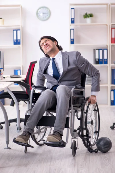 Young handsome employee in wheelchair working in the office