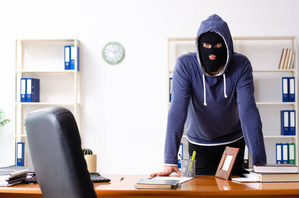Male thief in balaclava in the office 