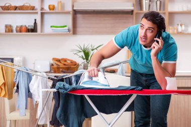 Genç adam evde çamaşır ütülüyor. 