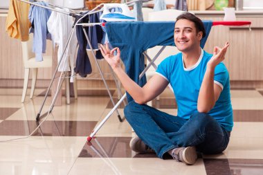 Young man husband doing clothing ironing at home  clipart
