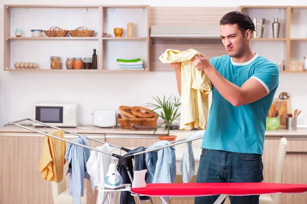 Joven marido haciendo planchado de ropa en casa — Foto de Stock