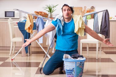 Genç adam evde çamaşır ütülüyor. 