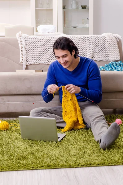 Young good looking man knitting at home