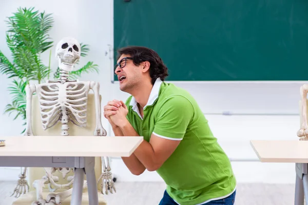 Grappige mannelijke student in de klas met skelet — Stockfoto