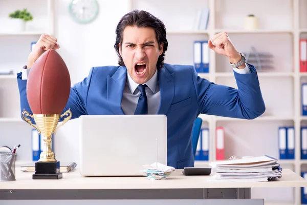 Joven hombre de negocios guapo con pelota de rugby en la oficina — Foto de Stock
