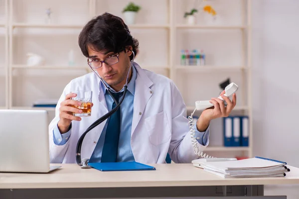 Young male doctor drinking in the office — Stock Photo, Image