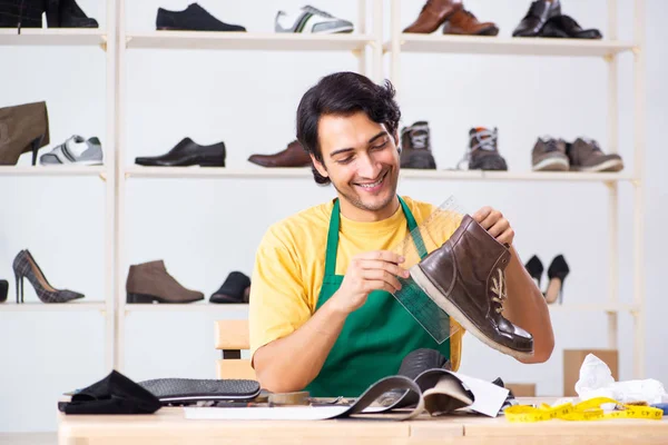 Young man repairing shoes in workshop