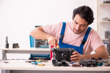 Genç bir erkek müteahhit bilgisayar tamir ediyor.  