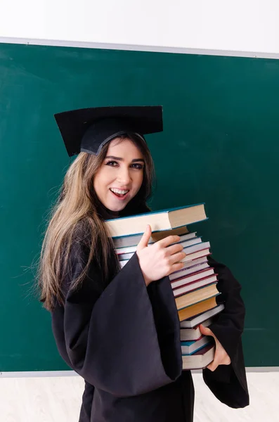 Estudiante graduada frente al tablero verde — Foto de Stock