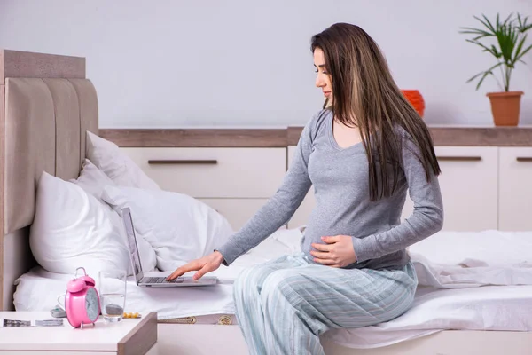 Jonge zwangere vrouw in de slaapkamer — Stockfoto