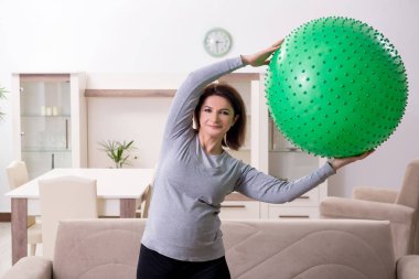 Evde egzersiz yapan yaşlı hamile bir kadın. 