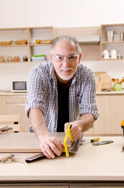 Betagter Lohnunternehmer, der in der Küche arbeitet — Stockfoto