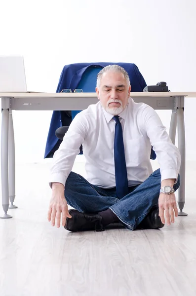 Homem de negócios envelhecido fazendo exercícios de ioga no escritório — Fotografia de Stock
