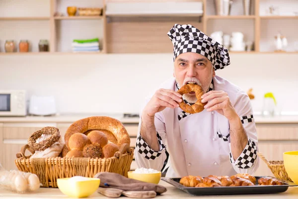 Old male baker working in the kitchen