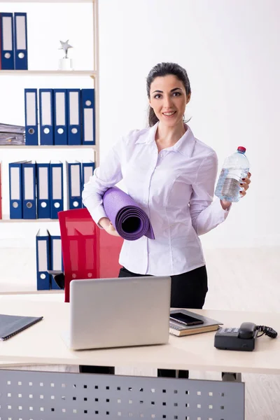 Jonge vrouwelijke werknemer doet oefeningen in het kantoor — Stockfoto