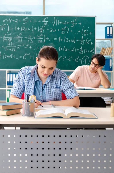 Jovens estudantes fazendo o exame de matemática em sala de aula — Fotografia de Stock