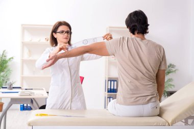 Kadın doktor hastaları goniyometre ile kontrol ediyor.