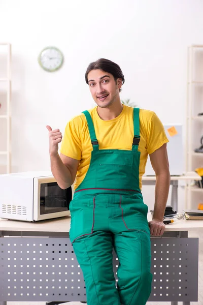 Young repairman repairing microwave in service centre