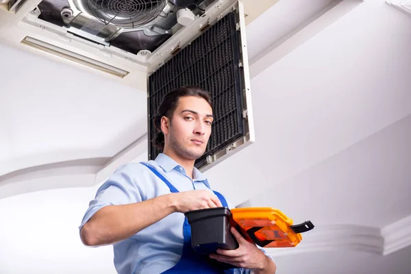 Jovem reparador reparando teto unidade de ar condicionado — Fotografia de Stock