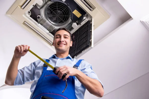 Young repairman repairing ceiling air conditioning unit