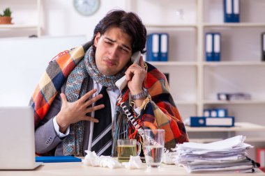 Ofiste grip olmuş bir adam çalışıyor.