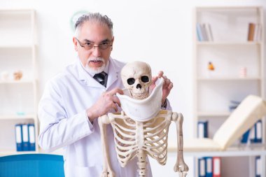İskeleti olan yaşlı erkek doktor. 