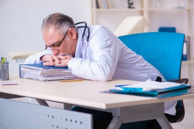 Klinikte çalışan yaşlı erkek doktor. 